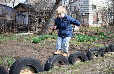 Little boy jumping on tires. - obrazy, fototapety, plakaty