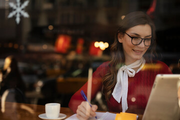 Beautiful young woman using digital tablet in cafe. Happy smiling woman enjoy in fresh coffee