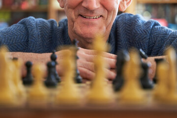 Problem solving concept. Senior man smiling at chess board