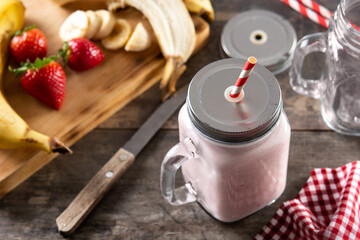 Fresh strawberry and banana smoothie in jar on wooden table