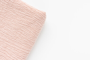 New folded soft pink fabric with puckered texture on white background. Fashion and clothes design and sewing concept