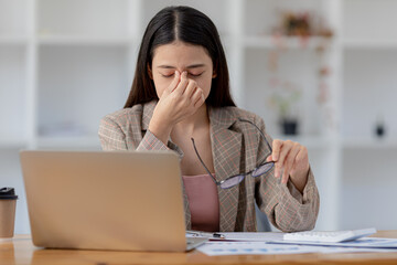 Beautiful Asian woman working in an office, she is a businesswoman who owns a company, she has a headache due to long and large paperwork leaving her tired and dizzy. The concept of sickness from work