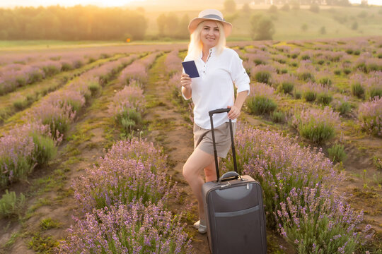woman with suitcase and passport in lavender field