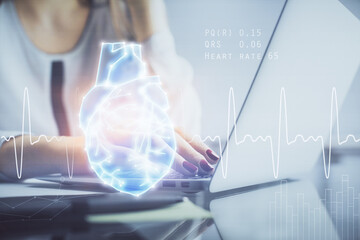 Double exposure of woman hands typing on computer and heart hologram drawing. Education concept.