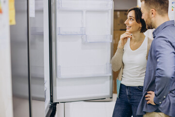 Young couple choosing refrigerator at store