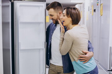 Young couple choosing refrigerator at store