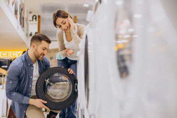 Couple choosing wasing machine at electronics store