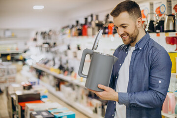 Man choosing electric kettle at store