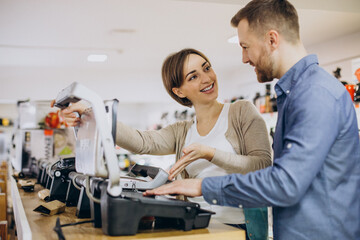 Naklejka premium Young couple choosing barbeque at electric store