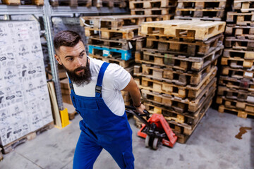 A storage worker is pulling a pile of pallets on a forklift. 