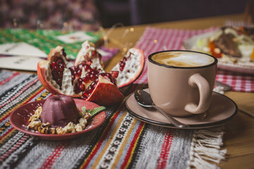 a cup of coffee on a table in a coffe shop in a beige mug . coffee with pomegranat, tea, restaurant, enjoy the taste dessert, cake, pastry, drink coffee, coffee to go,