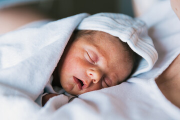 Fototapeta na wymiar Close up view of a cute newborn baby sleeping on his mother.