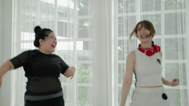beautiful Asian woman and fat woman practicing dancing in the room cheerful and happy. Concept of exercise and body weight loss

