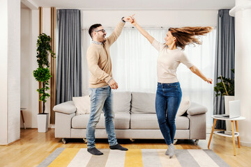 A playful couple dancing together at their new home.
