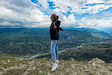 Naklejka premium A girl on the background of a breathtaking view of the mountains in Dagestan, Caucasus. Russia 2021