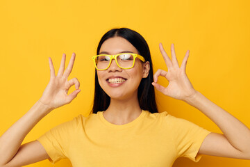 woman with Asian appearance in glasses gesturing with hands copy-space yellow background unaltered