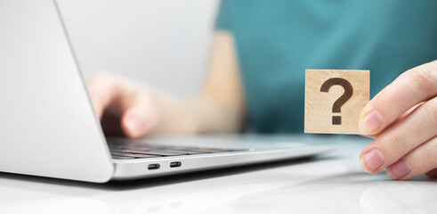 Customer care and support concept background. FAQ question mark icon on a wooden cube close-up...