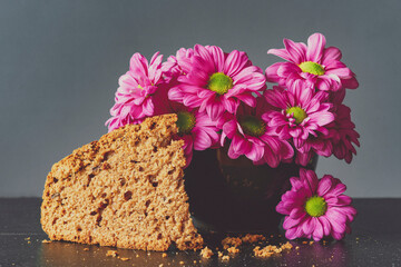 Ciasto piernik, różowe kwiaty, margaretki obok. 