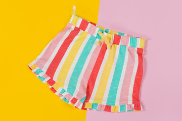 children's colored striped shorts, on a yellow and pink background, concept