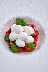 Tasty caprese salad with cherry tomatoes, white mozzarella cheese and green basil leaves