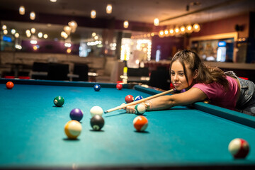 pretty caucasian woman playing snooker at pub