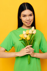 woman with Asian appearance green t-shirt a bouquet of yellow flowers yellow background unaltered