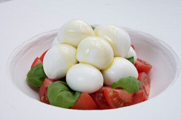 Tasty caprese salad with cherry tomatoes, white mozzarella cheese and green basil leaves