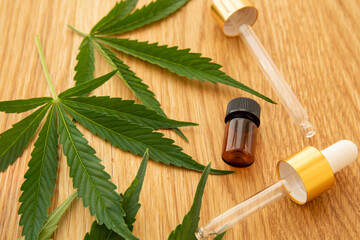 Medical cannabis oil concept image. Glass bottles and pipettes near natural cannabis leaves on...