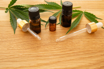Medical cannabis oil concept image. Glass bottles and pipettes near natural cannabis leaves on...