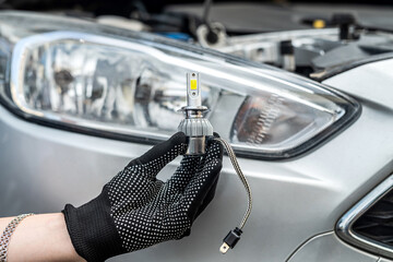 mechanic installing modern led H7 light bulb with wires in headlamp
