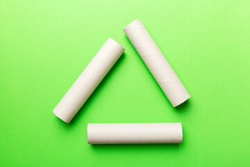 Empty toilet paper roll on colored background. Recyclable paper tube with metal plug end made of kraft paper or cardboard in the form of a recycling sign