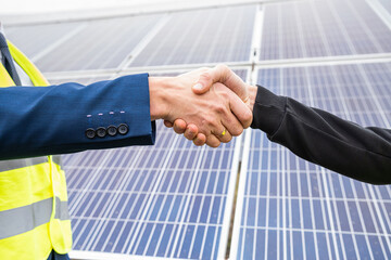 workers in  helmets two men shake hands after working on the installation of panels.