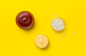 Bowl of salt, ketchup and cheese sauce on colored background, top view with copy space