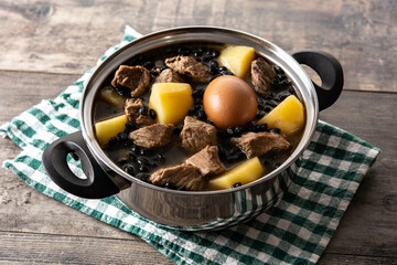 Traditional Jewish cholent in casserole on wooden table	