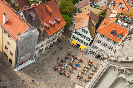 Unrecognisable people sitting at outdoors cafe on the Munsterplatz square in old town of Konstanz, Germany. Top view from the Tower of Konstanz Cathedral