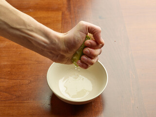 hands squeezing lemon juice to make a sauce in the kitchen