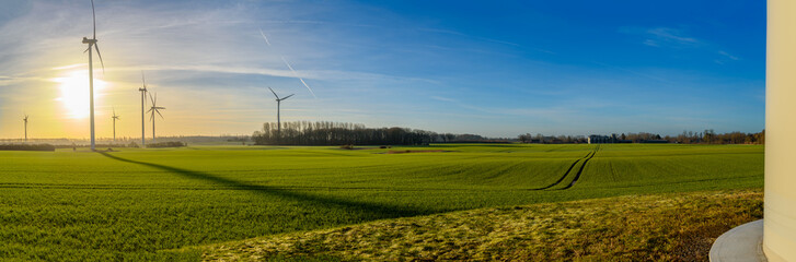 Landscape with wind turbines, green fields and an agricultural silo and a settlement in the...