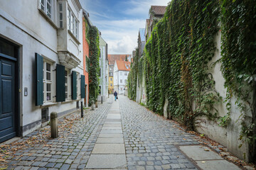 Obraz premium Bummel durch die romantische Altstadt von Augsburg mit Blick auf alte Häuser und eine von Efeu bewachsene, alte Mauer in der Schwabenstadt in Bayern, Deutschland.