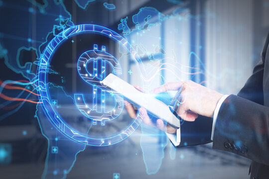 Close up of businessman hand using tablet with abstract glowing blue dollar sign and map with charts on blurry office interior background. Currency, trade and digital market concept. Double exposure.