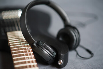 Black headphones on black electric guitar. Musical lifestyle.	