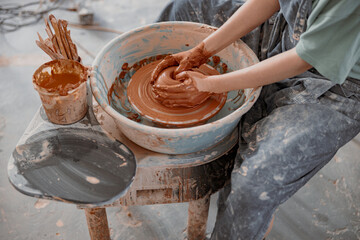 Experienced woman works on pottery wheel in ceramics workshop
