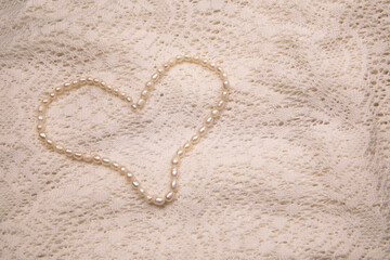 Valentine's Day image with white perl necklace in heart shape on a white lace background