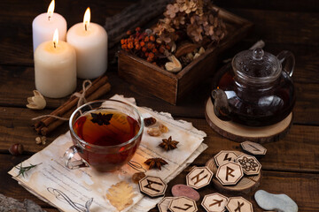 Wooden runes are lying on the table among the papers with notes. There is a mug of tea next to it....