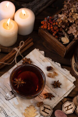 Wooden runes are lying on the table among the papers with notes. There is a mug of tea next to it. Astrology and esotericism.