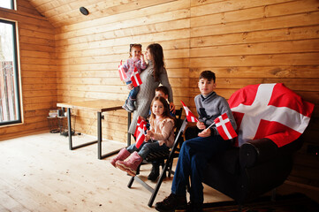 Family with Denmark flags inside wooden house. Travel to Scandinavian countries. Happiest danish people's .