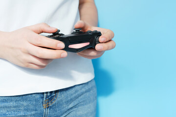 Female hands holding video game joystick on blue background, front view.
