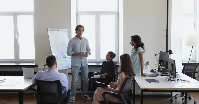 Diverse businesspeople, employees attending in teambuilding meeting, business training led by Hispanic coach, provide information, share knowledge during seminar in company office. Teamwork concept