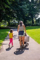 Back view of a woman walking in the city park together with her young daughter.