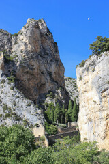 View to the rocks and scarps above the surrounding wall of the village Moustiers-Sainte-Marie near Canyon Gorge du Verdon, Provence, France with its symbol, a golden star at the blue sky 
