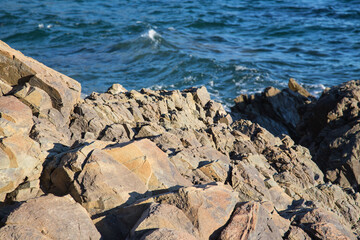 Red brown jagged rocks in front of the blue crystalline mediterranean -  the rocky hiking trail Sentier du Littoral in the beautiful nature reserve at the peninsula Saint Tropez